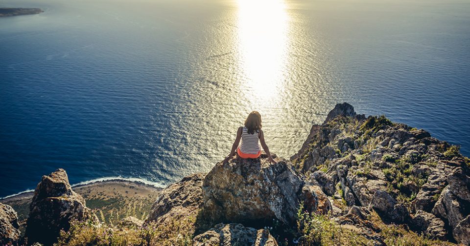 Panorama visto dalla vetta della Riserva di Monte Cofano a Custonaci. In primo piano una ragazza seduta sulle rocce, sul fondo il mare.