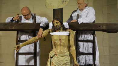 Due uomini vestiti di bianco staccano il crocifisso dalla croce per consegnarlo alla venerazione dei fedeli.