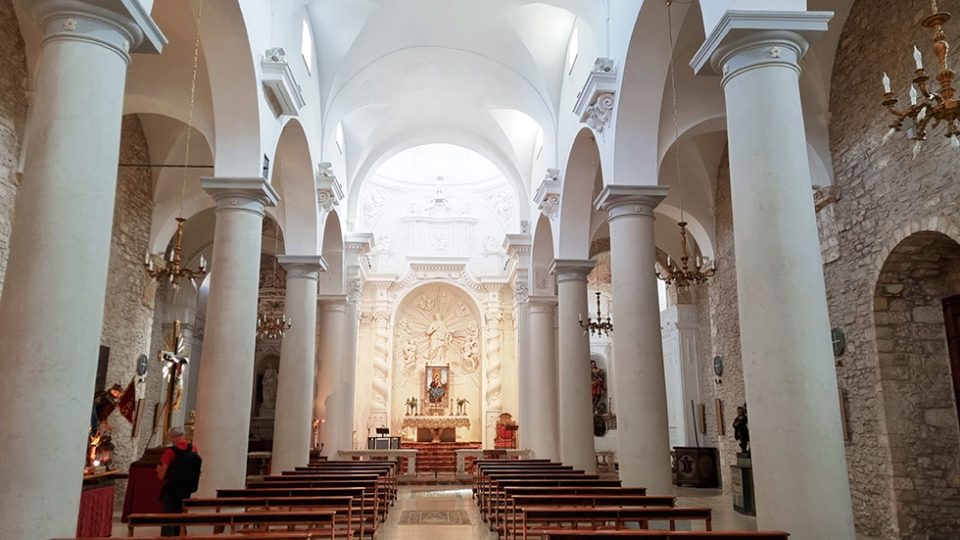 Interno della chiesa di San Giuliano. Colonne con archi e stucchi bianchi.