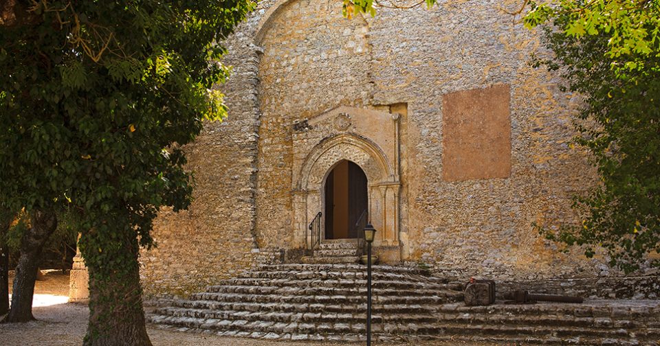 Prospetto laterale della chiesa di San Giovanni a Erice. Mura in pietra con portone ad arco acuto e scalinata a ventaglio.